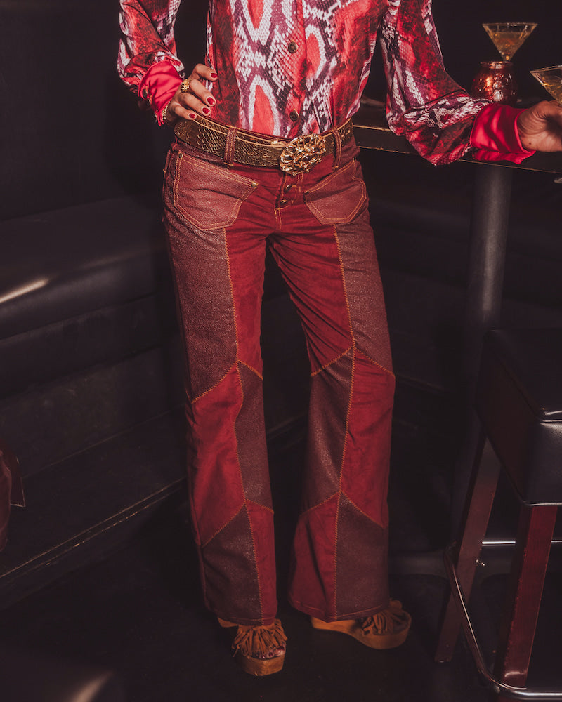 Person wearing a red patterned shirt and red pants in a dimly lit room.