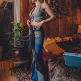Woman in a room with wooden walls and a patterned rug, wearing a blue top and jeans.