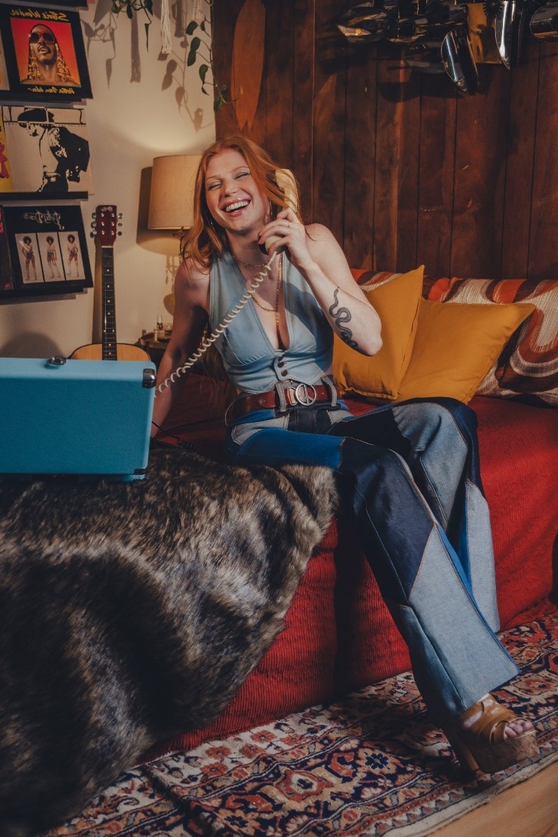 Woman sitting on a red couch in a cozy living room, talking on a vintage phone.