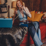 Woman sitting on a red couch in a cozy living room, talking on a vintage phone.