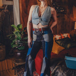 Woman in a stylish outfit standing in a room with wooden walls and a plant.