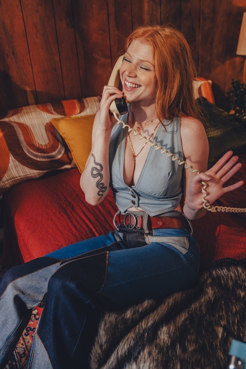 Woman sitting on a couch talking on a phone in a cozy room.