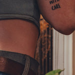 Person wearing a tattoo on their arm with the text 'HANDLE WITH CARE' against a blurred background.