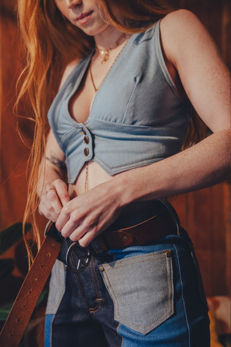 Person wearing a blue sleeveless top and jeans with a blurred background