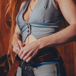 Person wearing a blue sleeveless top and jeans with a blurred background