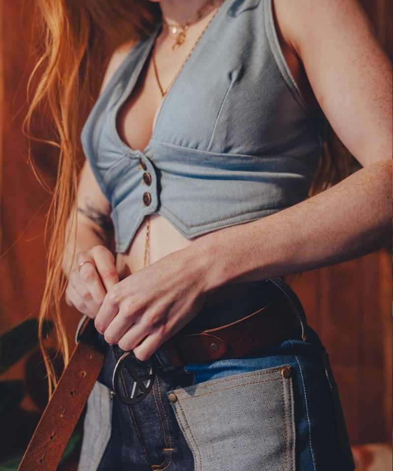 Person wearing a blue sleeveless top and jeans with a blurred background