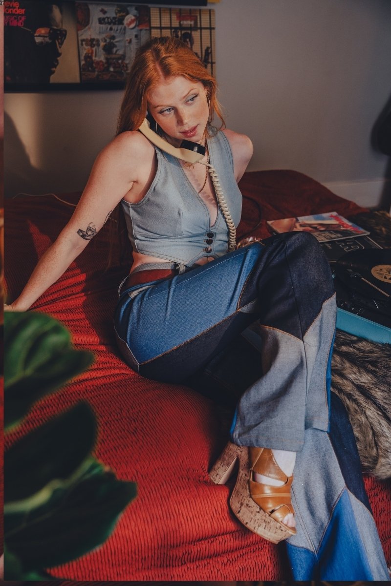 Woman sitting on a red couch with a phone to her ear, surrounded by vinyl records and a plant.