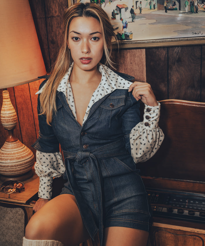 retro fashion moment with a woman in a denim romper next to a spinning record in a cozy vintage home