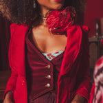 Woman wearing a red retro inspired outfit with a burgundy stylish waistcoat, sitting indoors.