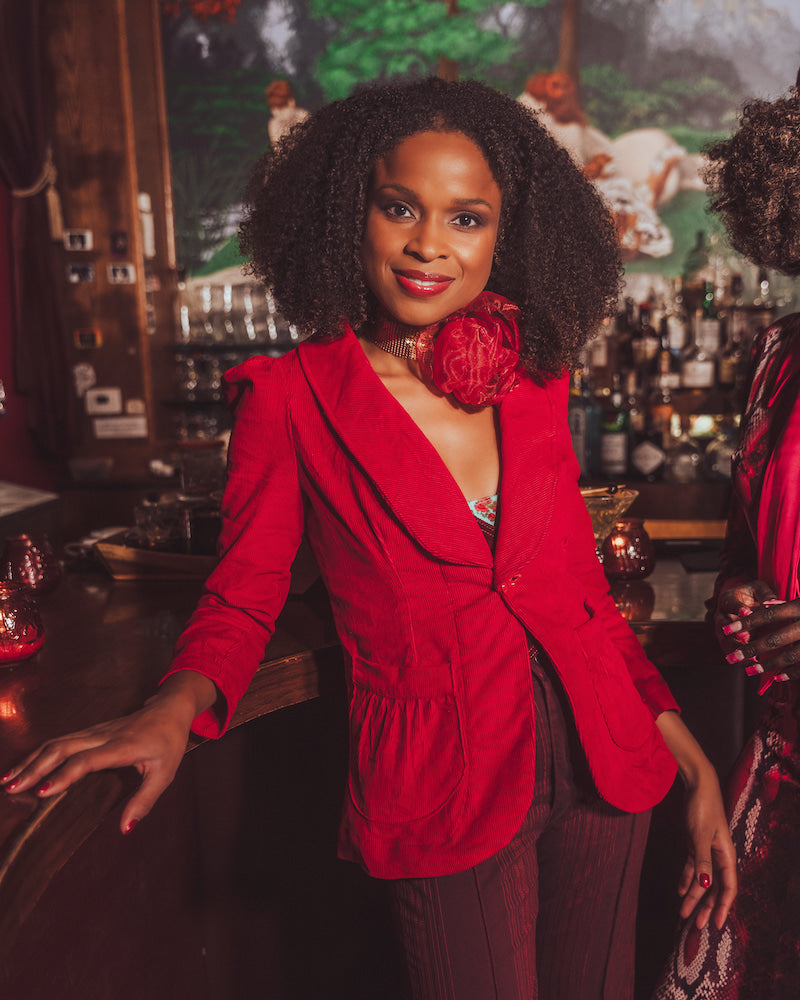 woman standing at a bar wearing red french blazer