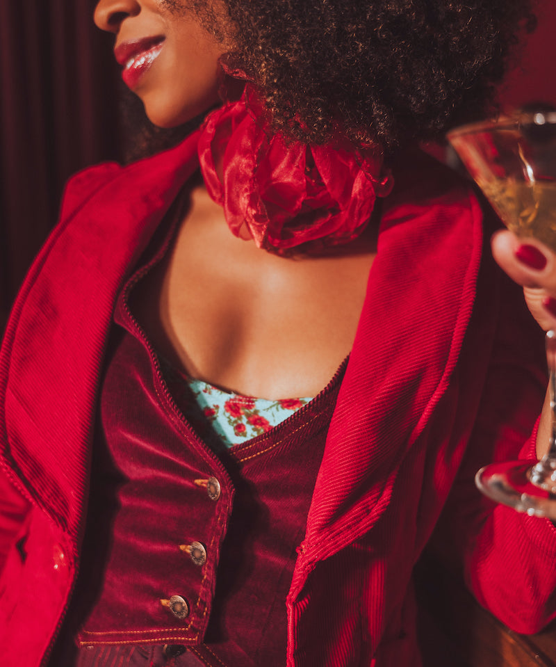 Woman in a red jacket holding a glass of champagne with a blurred background