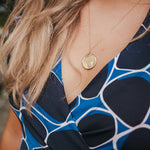 Close-up of a person wearing a blue patterned top with a gold necklace wearing Soul Sister since 1969..