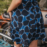 Person wearing a blue and black patterned dress with a vintage motorcycle and suitcase in the background wearing Soul Sister since 1969..
