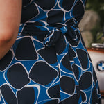 Close-up of a person wearing a blue and black patterned dress wearing Soul Sister since 1969..