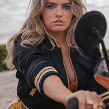 Woman on a motorcycle wearing a black and yellow jacket with sunglasses on her head Soul Sister since 1969 .