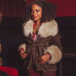 Woman wearing a brown coat with fur trim in a theater setting