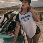 Woman wearing a 'Ride or Die' t-shirt leaning against a car in a desert setting wears clothing by Soul Sister since 1969