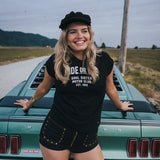 Woman standing next to a vintage car wearing a black t-shirt with text Ride or Die Motor Club wearing soul sister since 1969