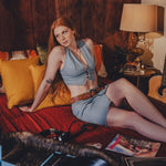 Woman sitting on a bed with a record player and vinyl records in a cozy room.