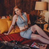 Woman sitting on a couch in a cozy room with a lamp and records.