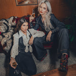 high waisted bell bottoms and tailored waistcoat steal the show as 2 women lounge in a throwback 70s home setting