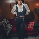 stylish woman in black flared trousers and matching waistcoat lounges in a retro home filled with retro charm