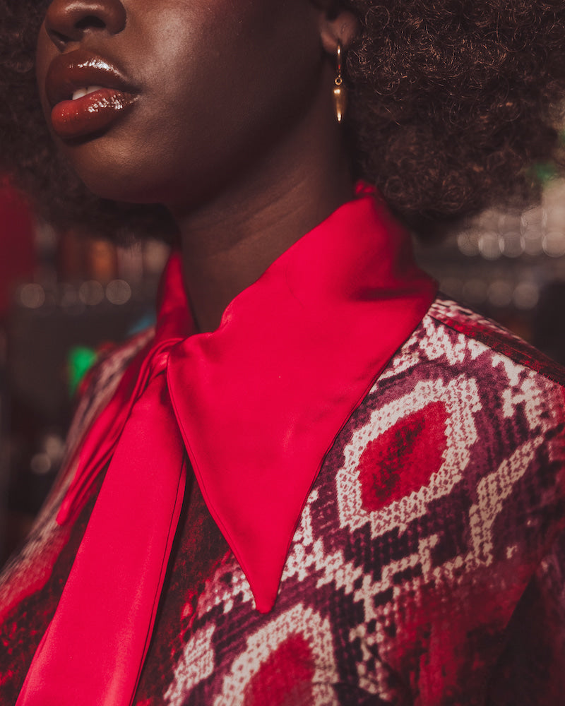 Close-up of a person wearing a patterned garment with a bright red bow tie.