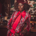 Woman in a stylish outfit with a red tie and patterned coat in a bar setting