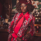 Woman in a stylish outfit with a red tie and patterned coat in a bar setting