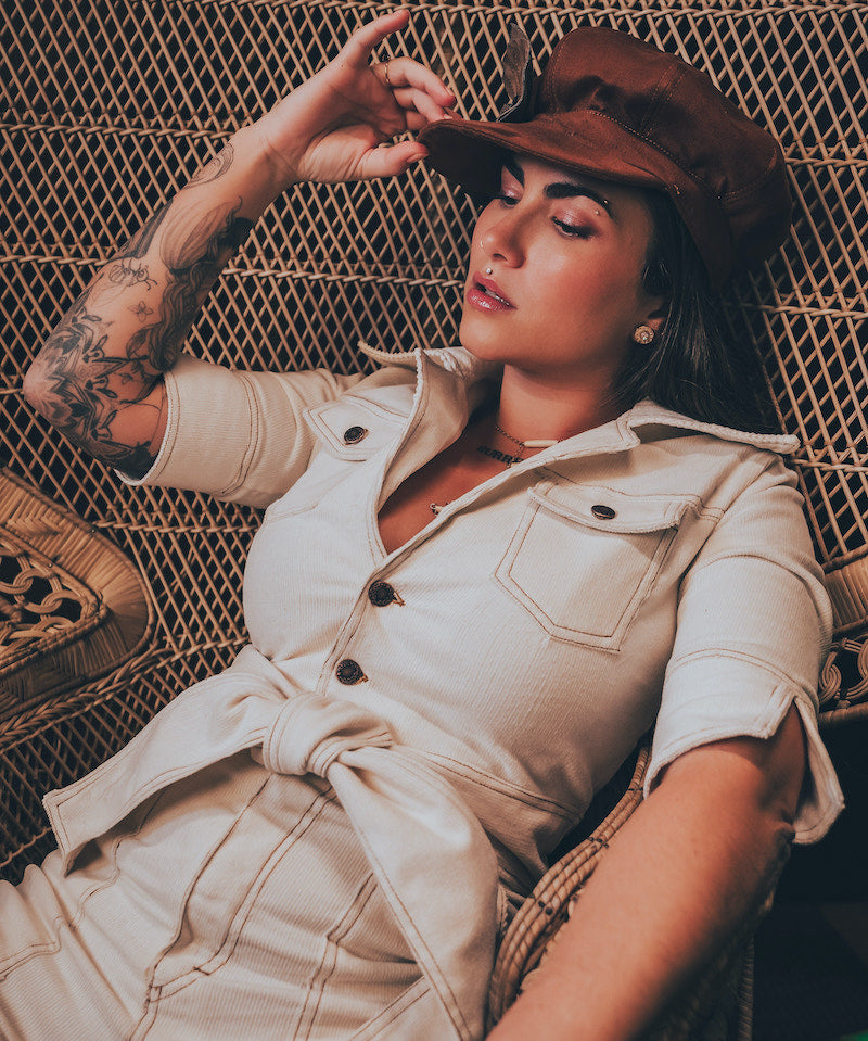 Model in a cream corduroyed jumpsuit capturing 70s retro style with long flared legs and tailored  top