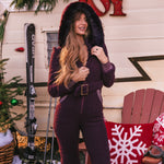 Woman in a purple outfit standing in front of a Christmas-themed trailer with skis and a chair.
