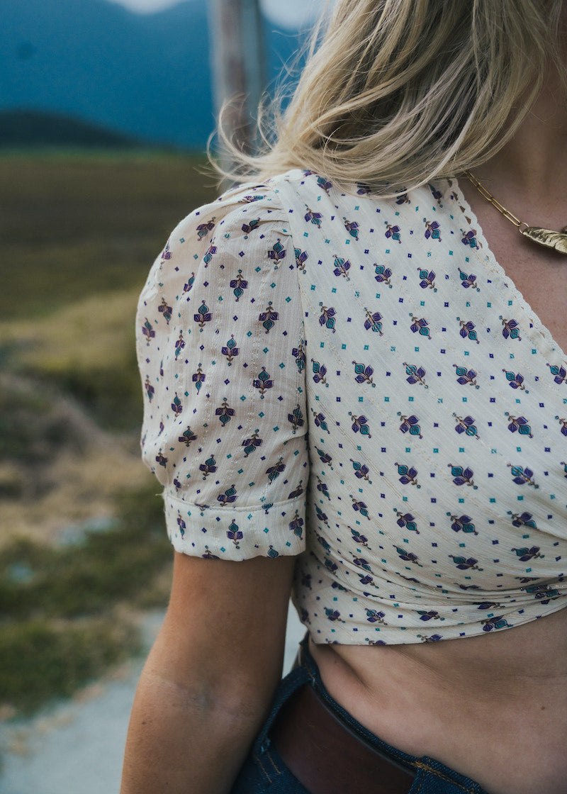 Person wearing a floral blouse with a blurred natural background wearing Soul Sister since 1969.