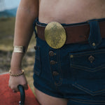 Person wearing a gold belt buckle and denim shorts with a blurred background wearing Soul Sister since 1969.

