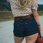 Person wearing a patterned shirt and denim shorts with a blurred natural background wearing Soul Sister since 1969.