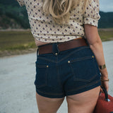 Person wearing a patterned shirt and denim shorts with a blurred natural background wearing Soul Sister since 1969.