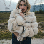Woman wearing a fluffy white jacket in an outdoor setting with power lines in the background wearing soul sister since 1969