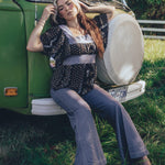 Girl sits at the front of a 1970s VW Van wearing 70s fashion jeans and blouse
