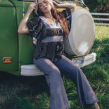 Girl sits at the front of a 1970s VW Van wearing 70s fashion jeans and blouse
