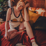 Woman in a soulful log  jersey sitting on a couch with a retro phone and plant in the background