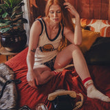 Woman sitting on a bed in a 1970s  inspired room with wooden walls and decor