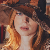 Person wearing a large, decorative hat with a leopard print pattern.