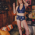 Woman in a blue star patterned 1970s diso ready outfit standing in a room with retro posters and decor.