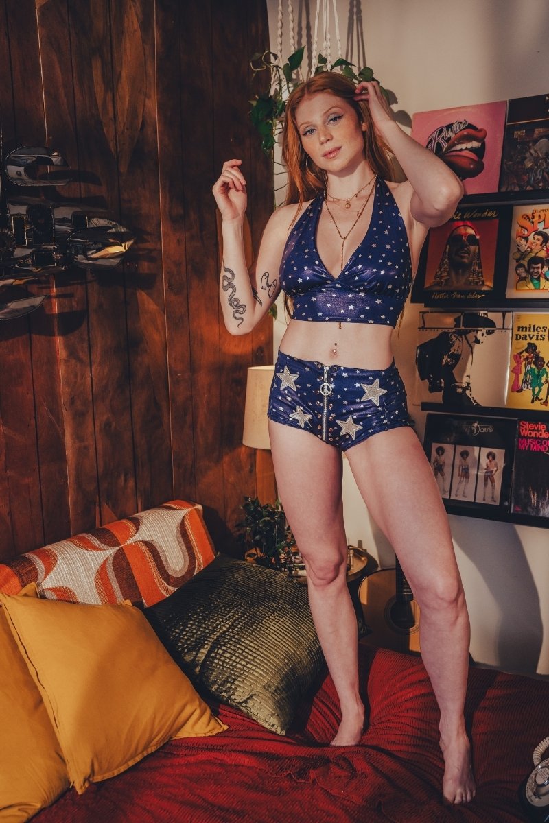 Woman in a blue and white star-patterned outfit standing in a room with a couch and decorative items.