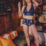 Woman in a blue and white star-patterned outfit standing in a room with a couch and decorative items.