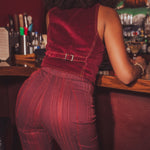 Person wearing a red bell bottom outfit standing at a 1970s styled bar counter.