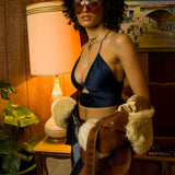 Beautiful woman in a retro 1970s living room wearing sunglasses and groovy jeans and halter top