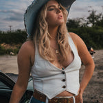 Woman in a white top and blue jeans with a cowboy hat standing next to a car outdoors Wearing Soul Sister since 1969.
