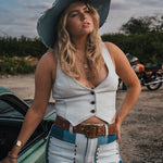Woman in a white top and blue jeans standing next to a green car with a motorcycle in the background wearing Soul Sister since 1969..