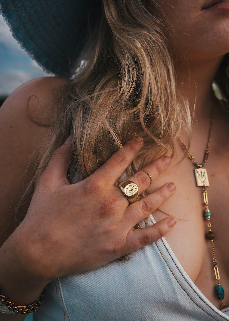 Close-up of a person wearing a ring and necklace with a blurred background wearing Soul Sister since 1969.