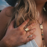 Close-up of a person wearing a ring and necklace with a blurred background wearing Soul Sister since 1969.